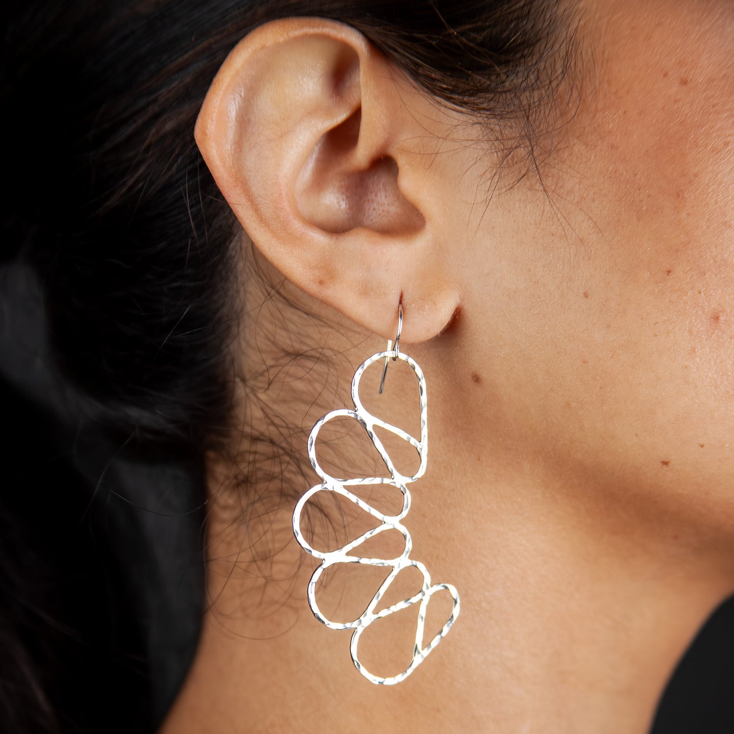 Close-up of a person wearing a spiral earring with a dark background
