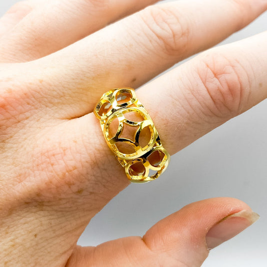 Gold ring on a finger against a neutral background