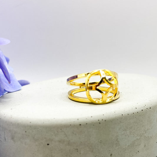 Gold ring on a concrete block with purple flowers in the background