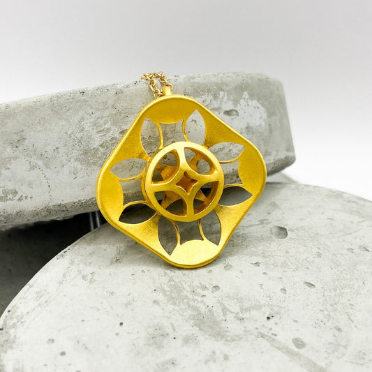 Gold pendant on a gray stone surface