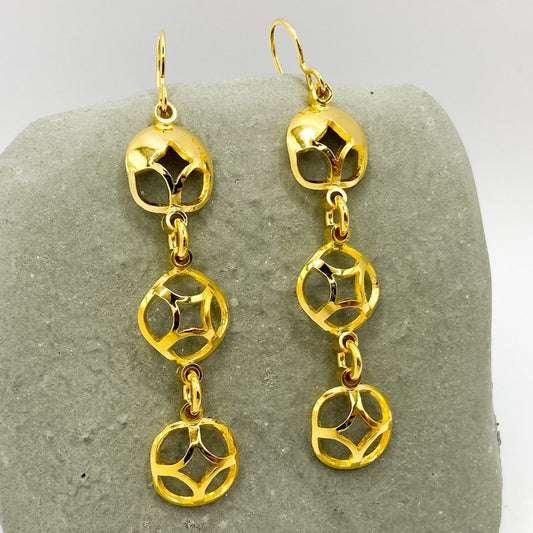 Gold chain earrings on a gray stone surface