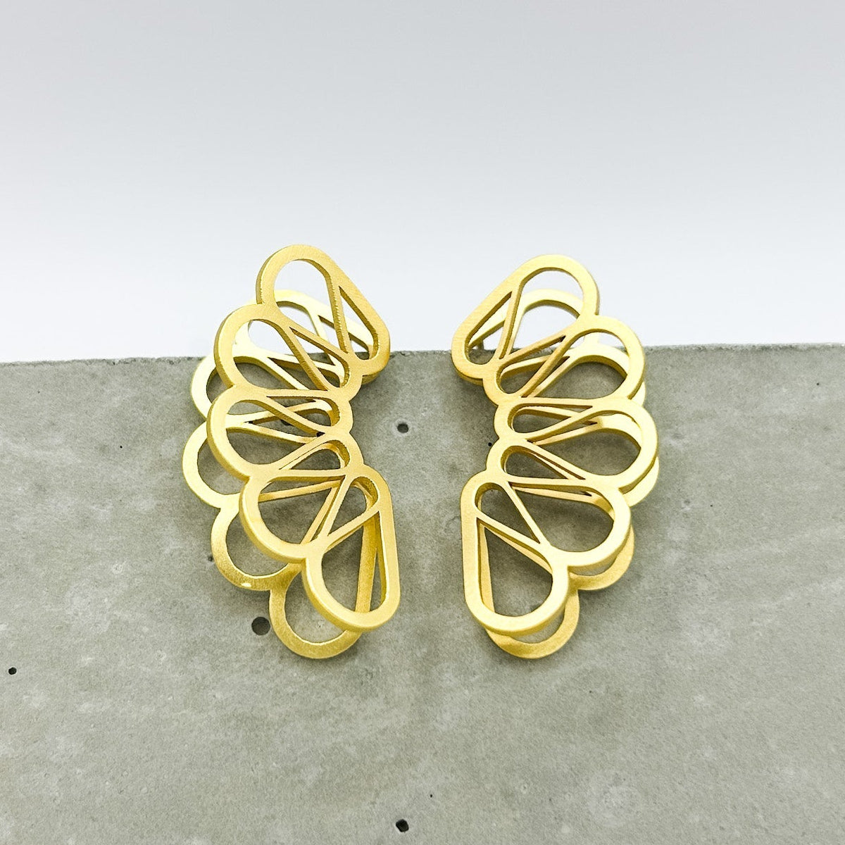 Gold earrings on a gray surface with a white background